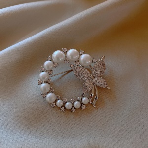 Broche circulaire dorée de perles